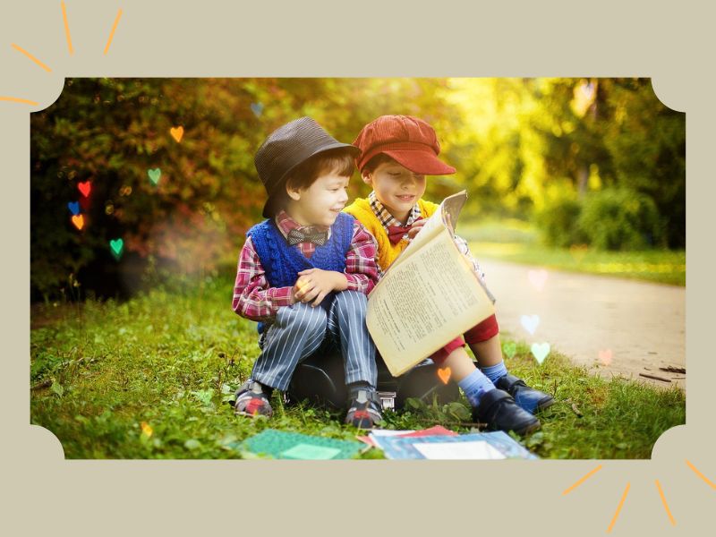 O que é literacia? Imagem de dois meninos lendo um livro, sentados na grama.