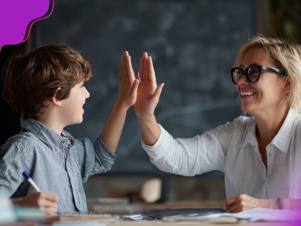 Professora e aluno batendo as mãos em um gesto de "toca aqui" transmitindo a sensação de celebração de uma conquista. A imagem ilustra a importância de dar devolutivas construtivas ao avaliar a intervenção pedagógica.