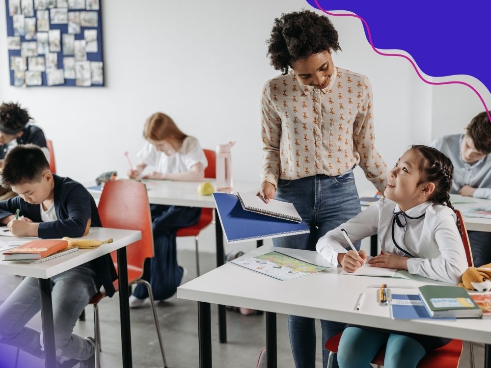 Professora com um caderno na mão interagindo com uma aluna para ilustrar a importância da avaliação contínua na superação das defasagens de aprendizagem.