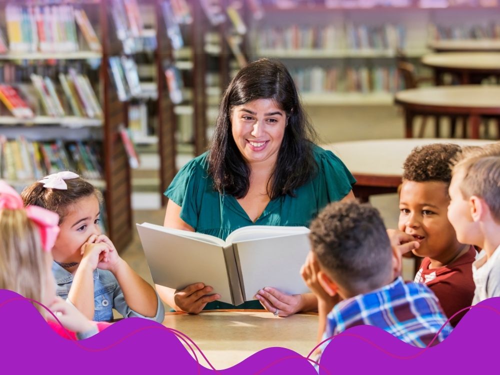 Professora lendo para os alunos para ilustrar a importância do(a) professor(a) ser um modelo de leitor para trabalhar a fluência em leitura com os alunos.